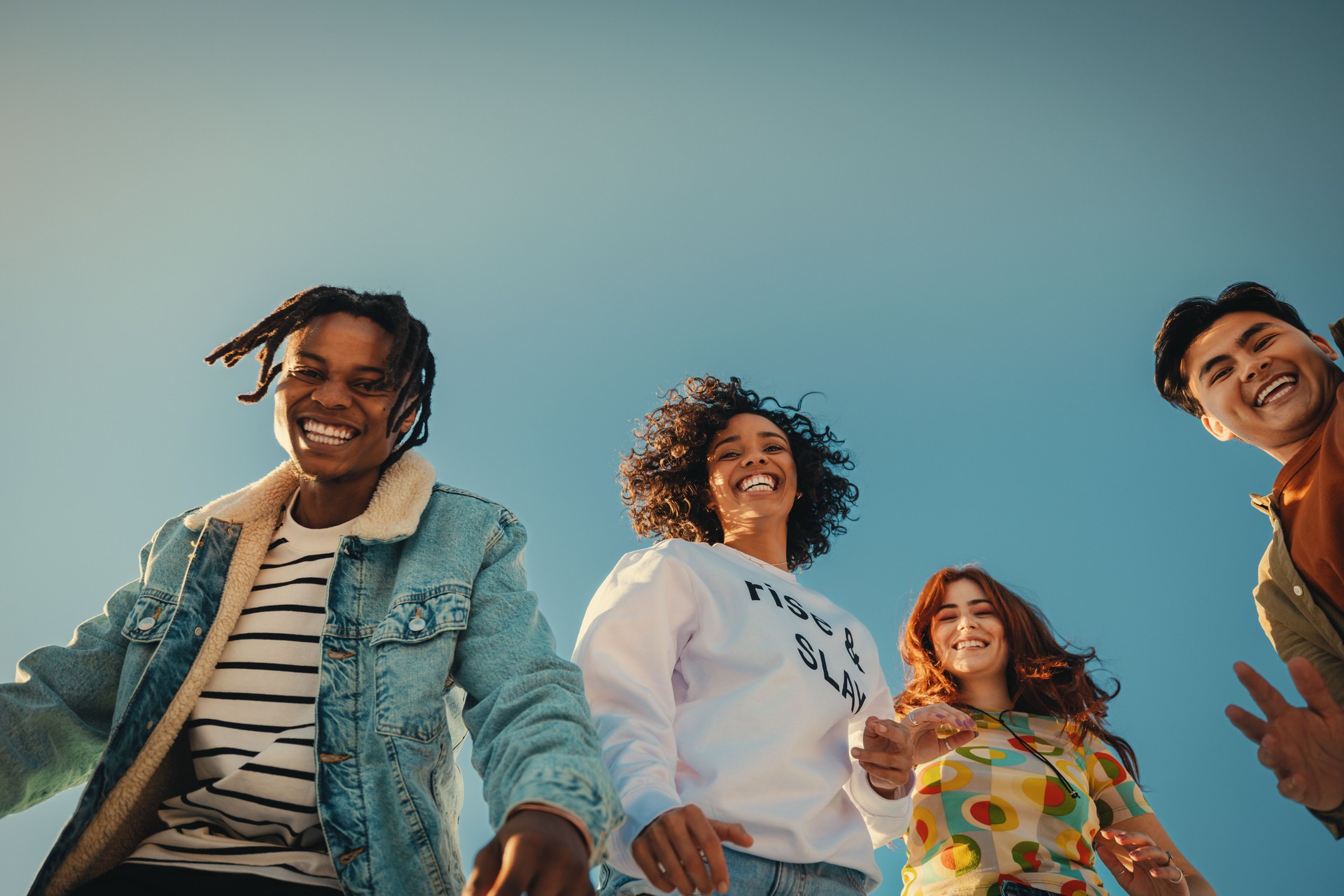 Happy young friends enjoying outdoor time together under blue sky