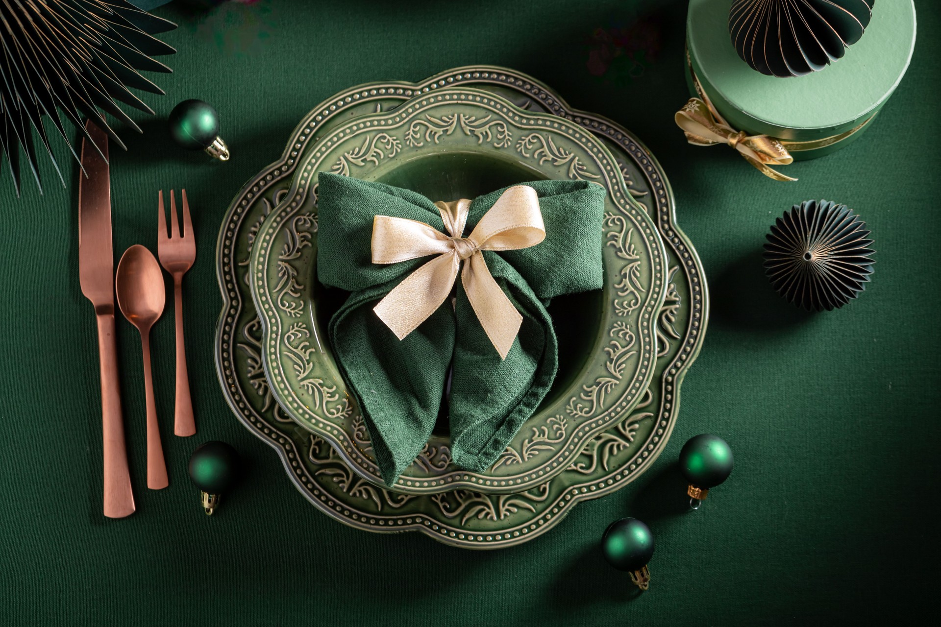 Contemporary dark green Christmas tableware with decorations and baubles.